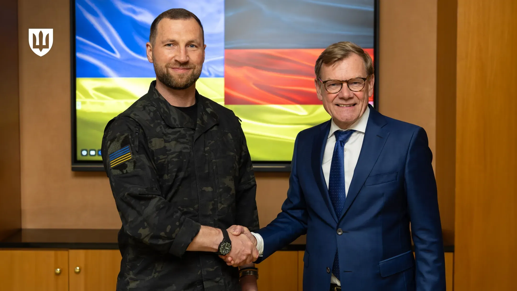 Євгеній Хмара та Йоганн Вадефул тиснуть руки на тлі екрана із зображенням прапорів України та Німеччини