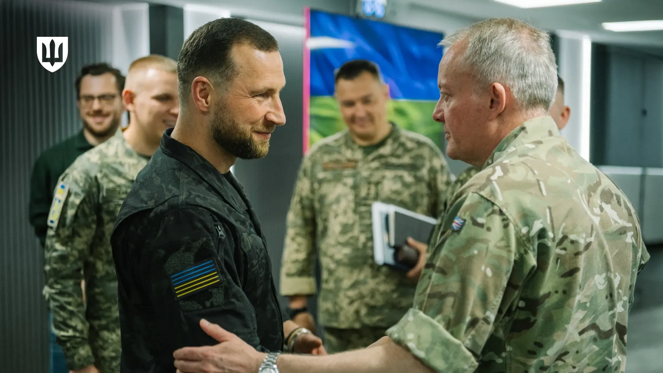 Evgeniy Khmara shakes hands with Air Chief Marshal Sir Richard Knighton in front of the Ukrainian and British flags