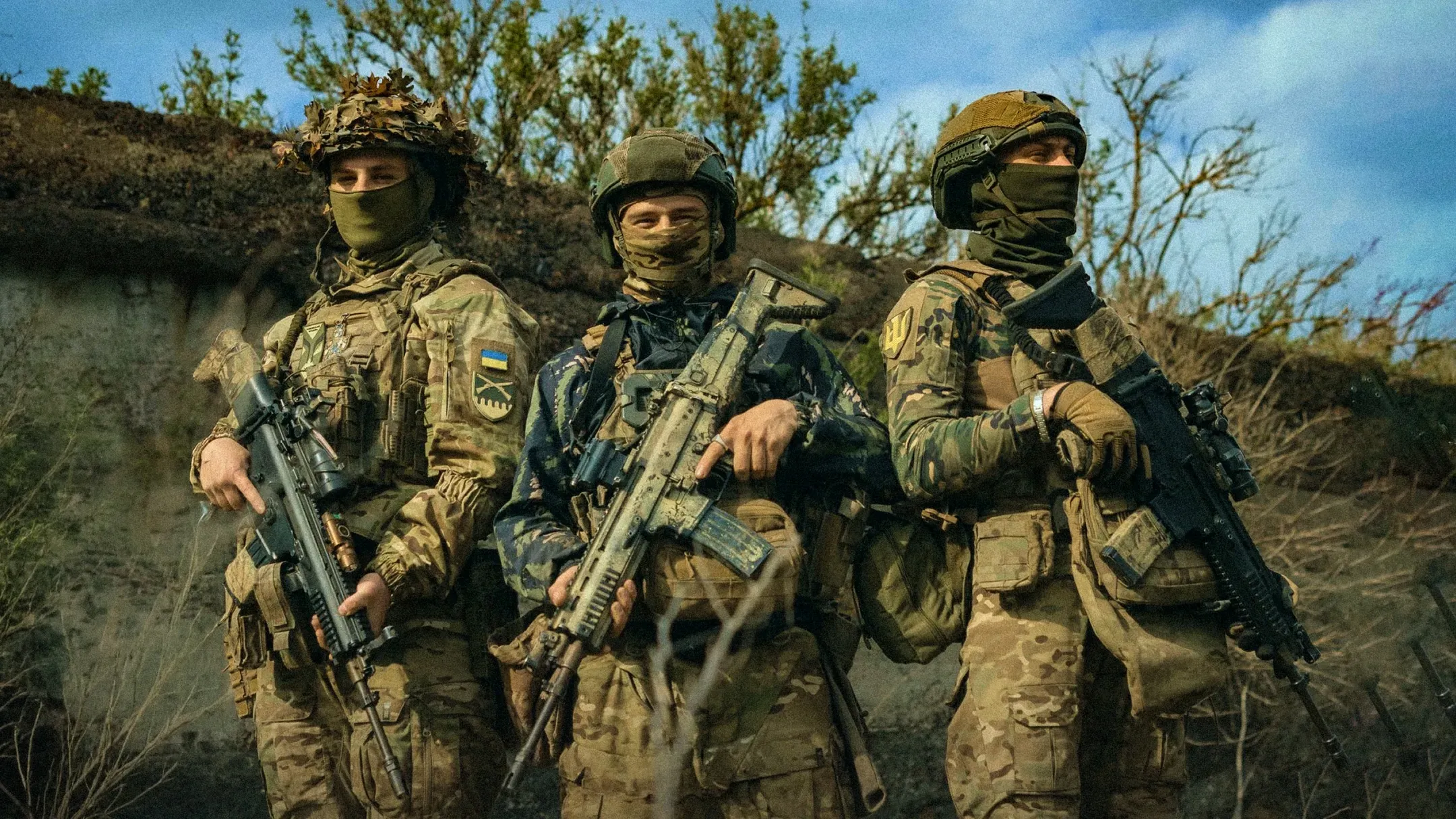 Троє українських військовослужбовців у повному екіпіруванні зі зброєю в руках