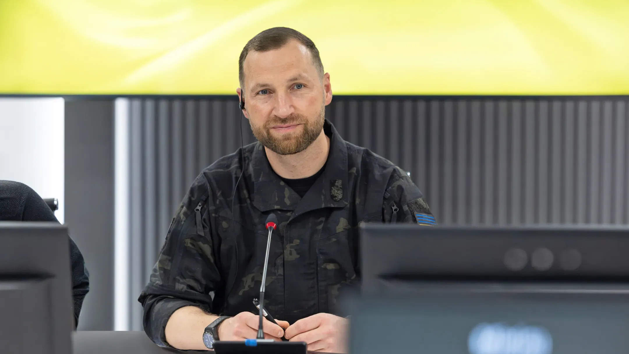 Evgeniy Khmara seated at a desk in front of a microphone and monitor