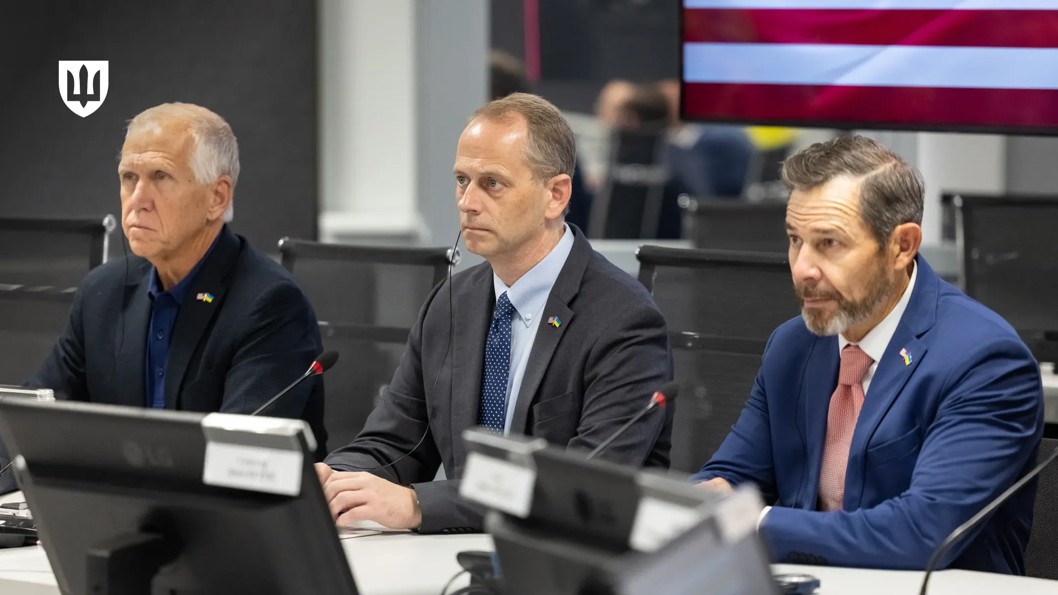 Представники делегації США за столом переговорів перед мікрофонами та моніторами