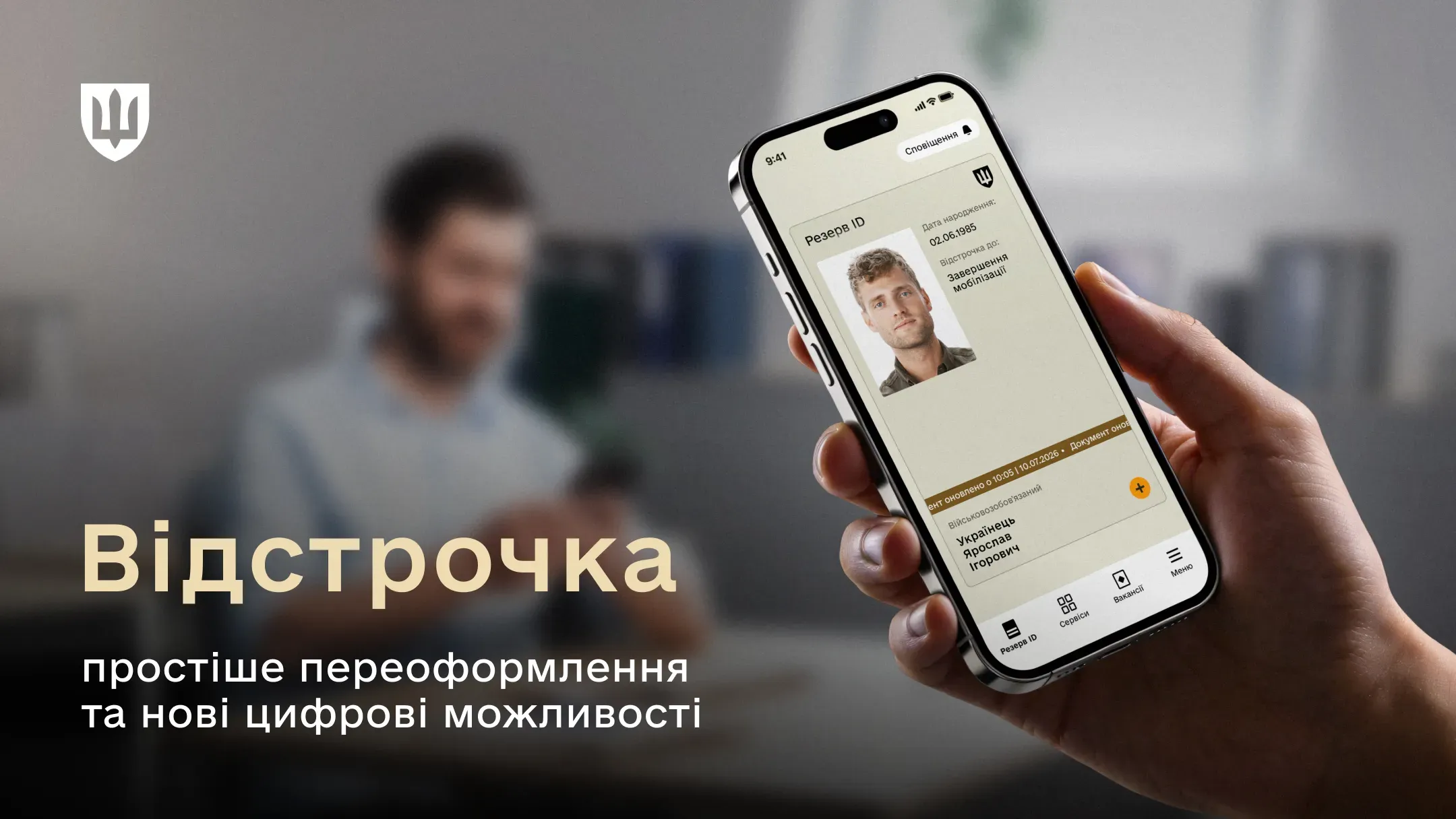 Рука тримає смартфон із відображеним на екрані електронним військовим документом зі статусом відстрочки від мобілізації на тлі розмитого силуету чоловіка