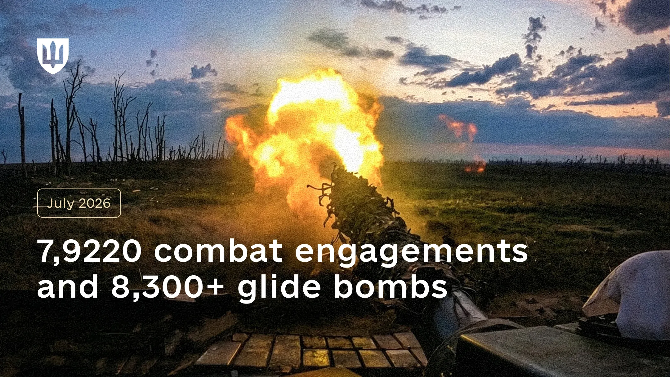 A tank with its barrel wrapped in camouflage netting fires at dusk across open ground, the muzzle flash lighting up a line of burnt, bare trees on the horizon
