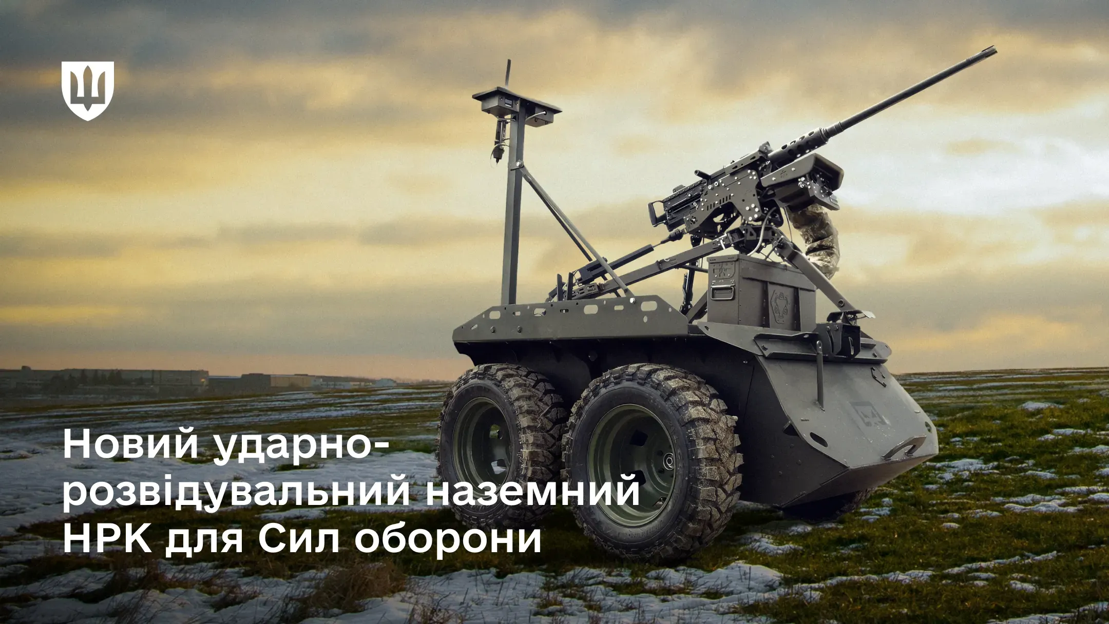 Наземний дрон Zmiy Droid 12.7  темно-оливкового кольору з великими позашляховими шинами стоїть на відкритій місцевості. На ньому встановлена турель з автоматичною зброєю, захищеною камуфляжним чохлом, та антена